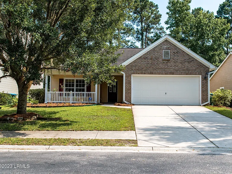A house with a driveway and trees in the background